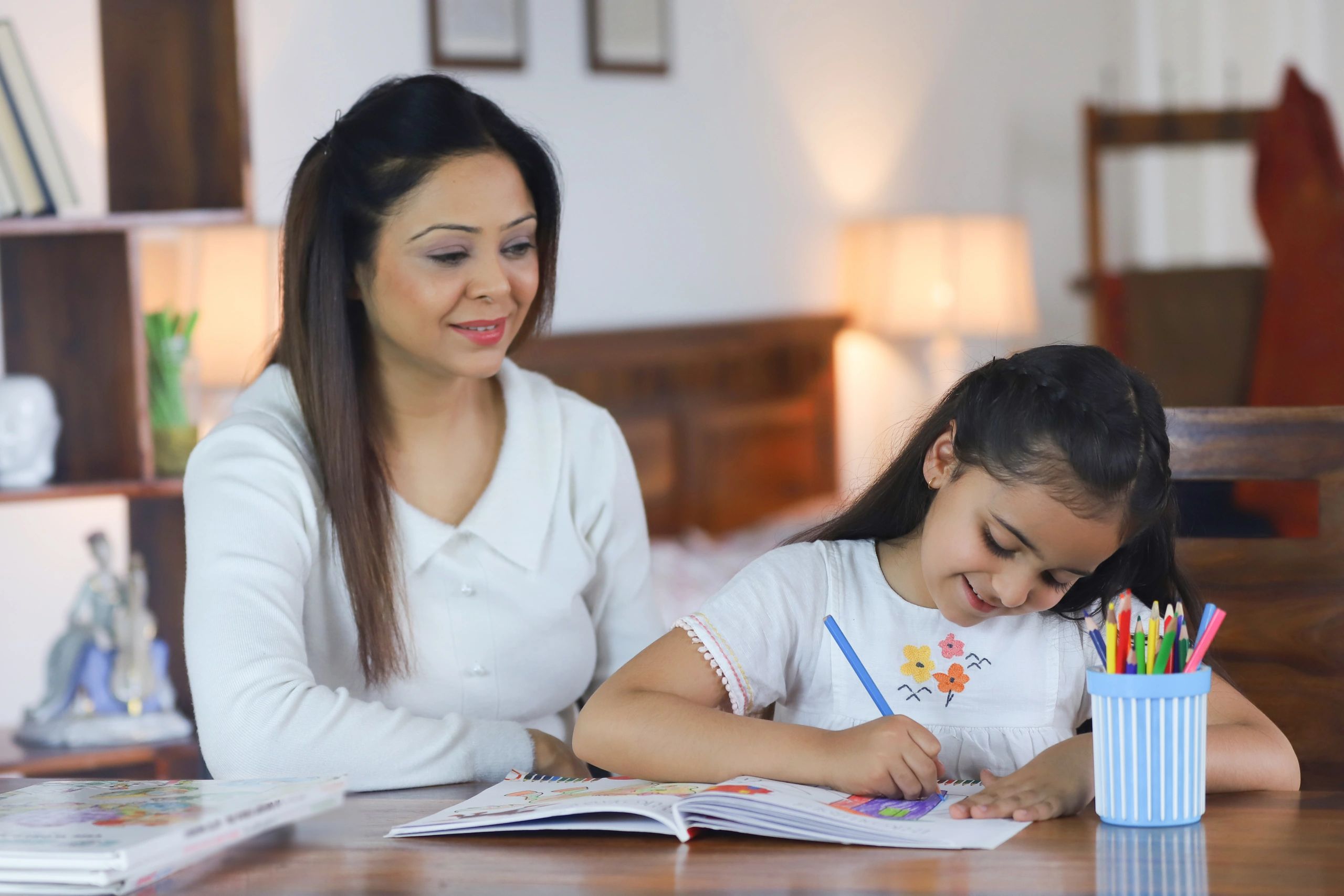 Mother helping child with workbook practice at home