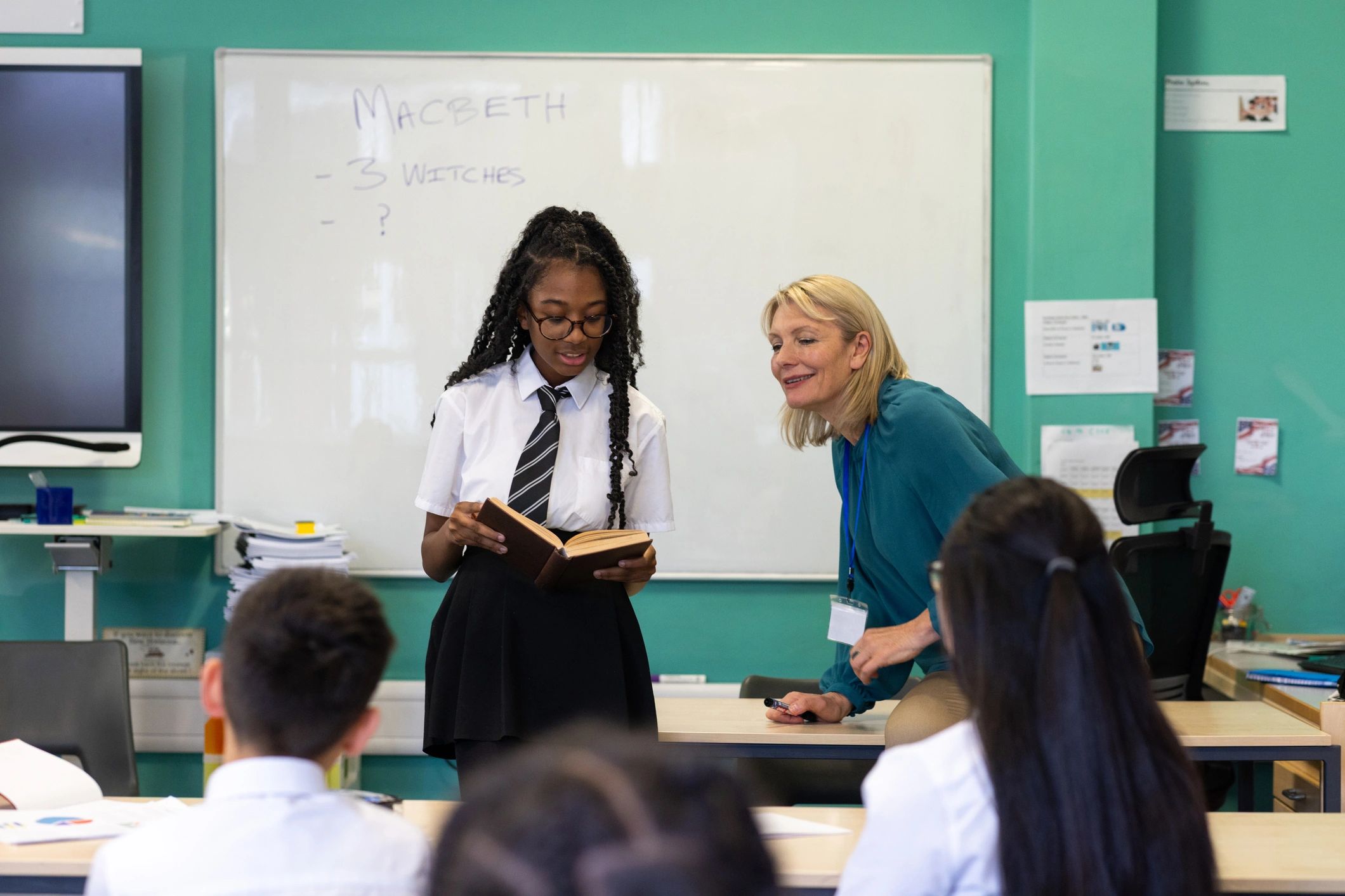 Student reading a book with teacher support
